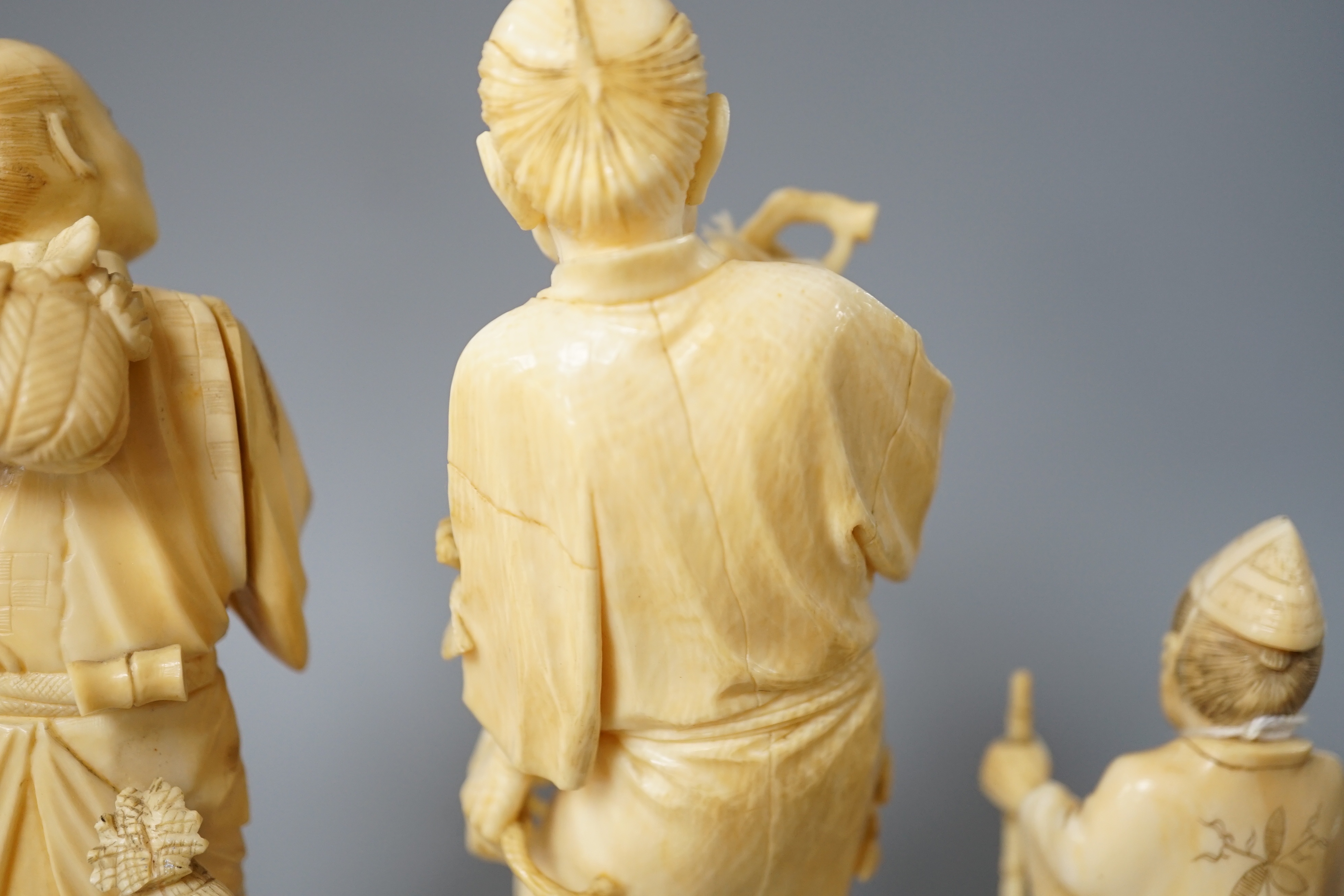 A 19th century Japanese ivory okimono of a gentleman holding a branch, another sectional figure of a gentleman with a walking stick, both signed and another 20th century okimono. Tallest 15.5cm